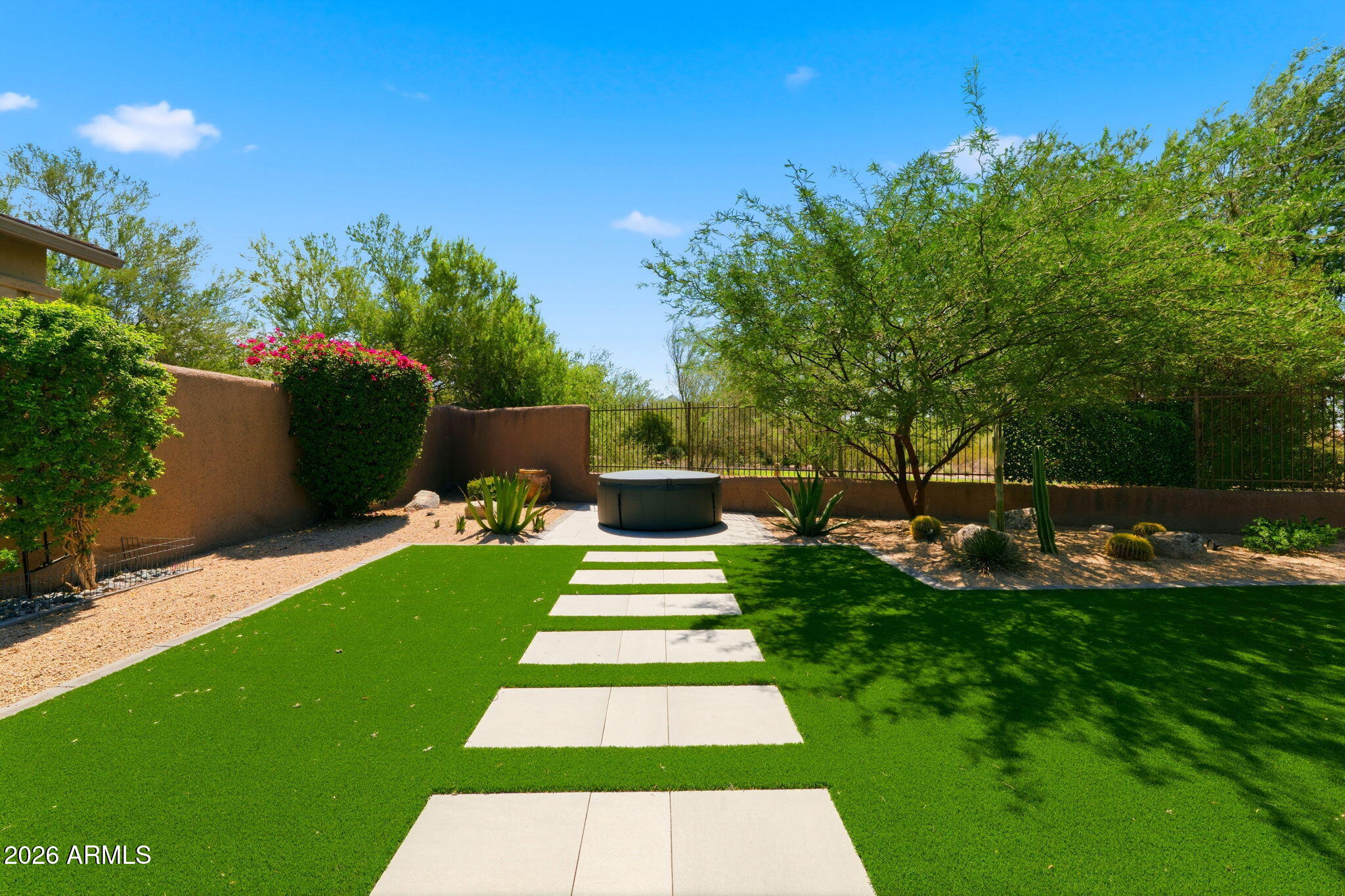 Low-maintenance backyard with turf lawn and paver walkway backing to common area