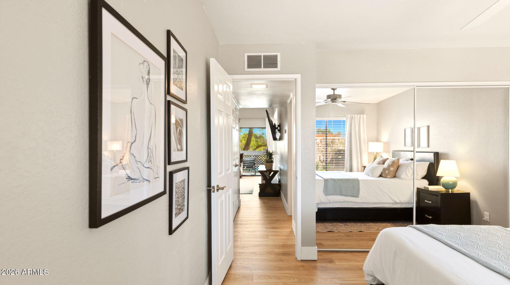 Bedroom with mirrored closet doors looking through to the living area