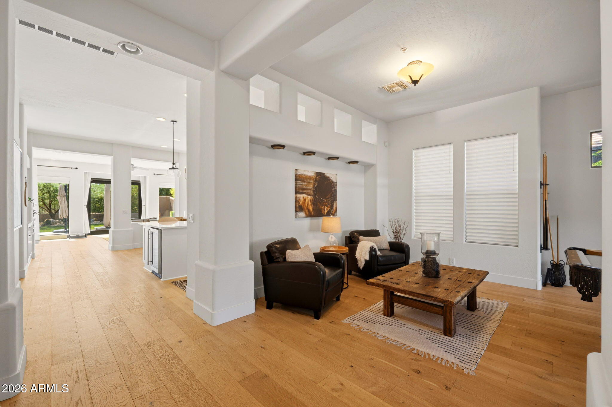 Open great room with light hardwood floors and sightlines to the rear yard